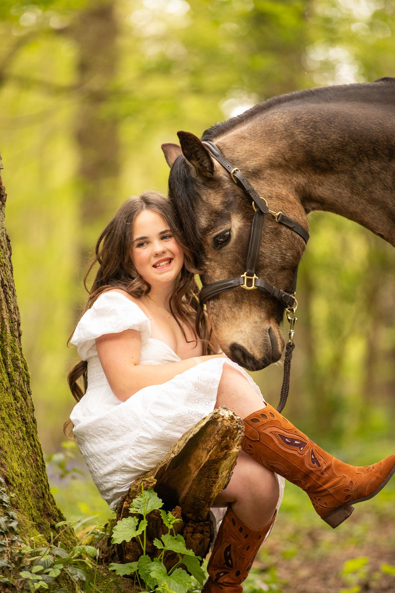 A bride in a white dress shares a tender moment with her horse against a blurred forest background.