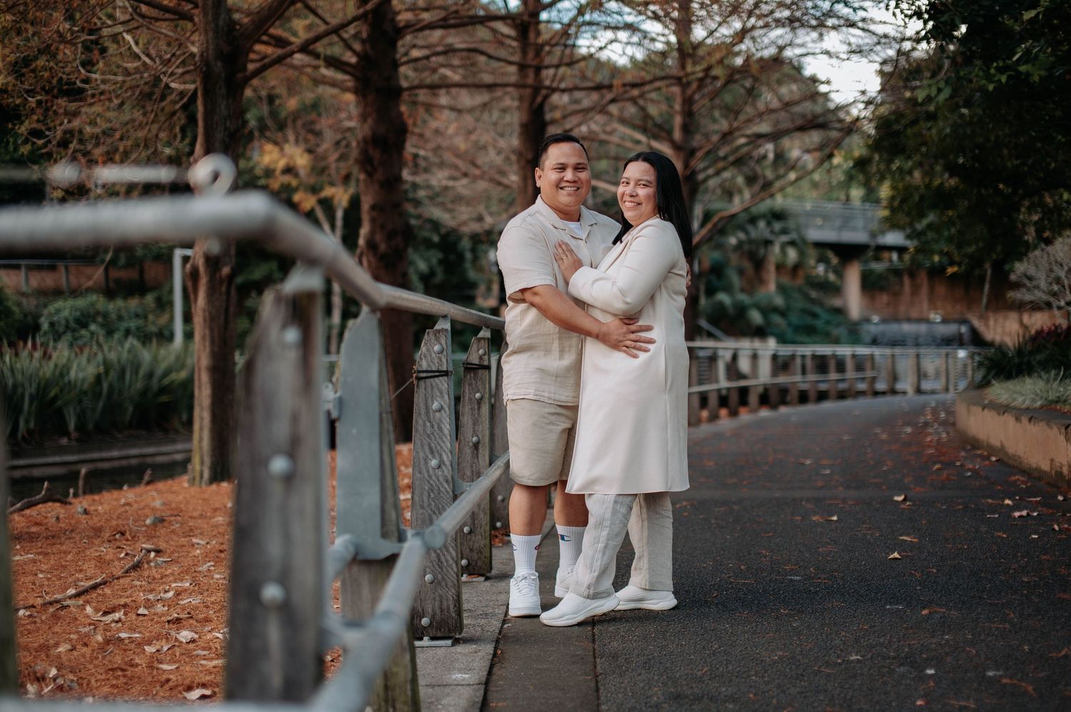Romantic couple share intimate moments in outdoor autumn setting with fallen leaves and stone path.