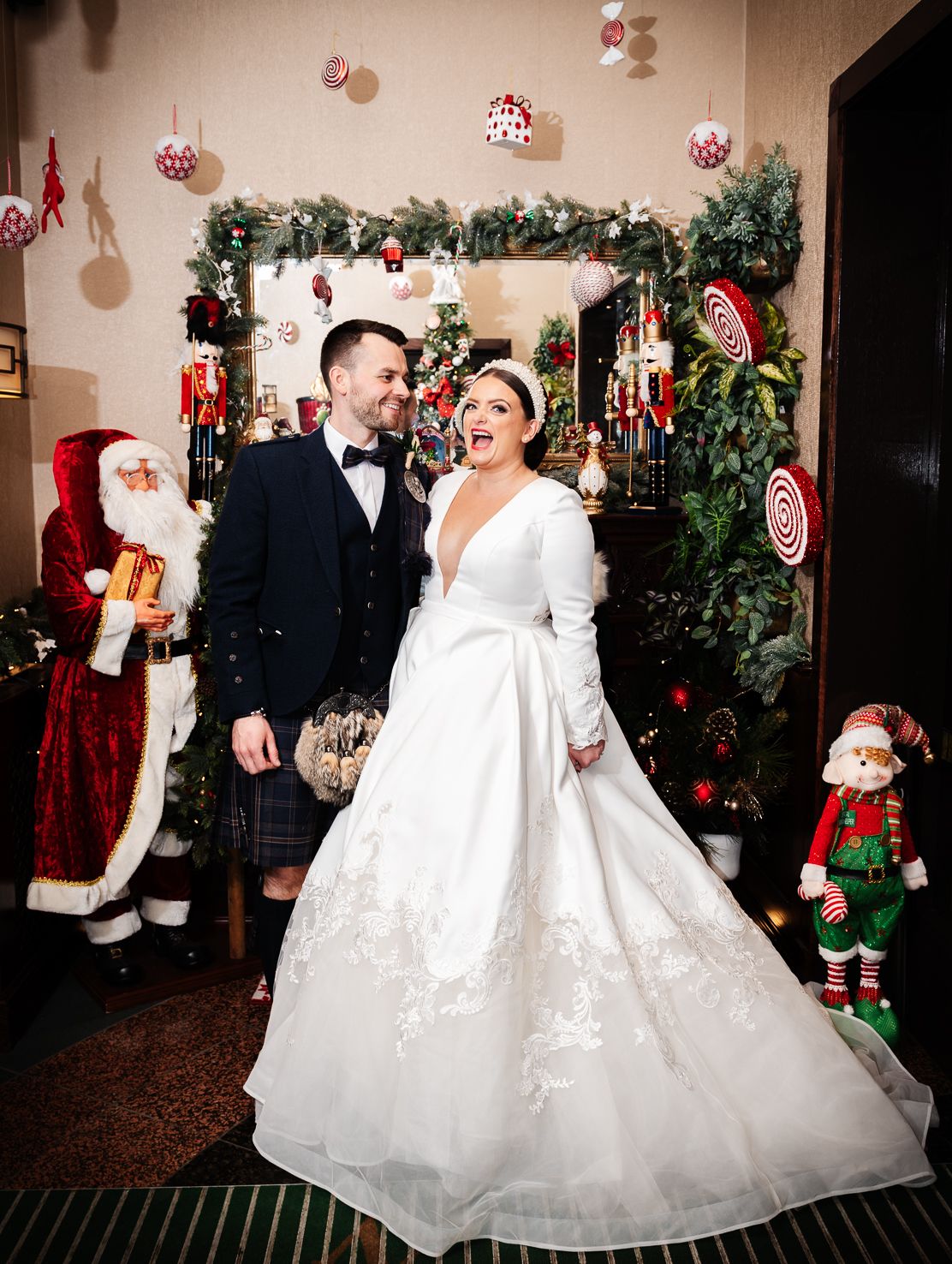 A winter wedding celebration with Christmas decorations and Santa figures in a festively decorated room.