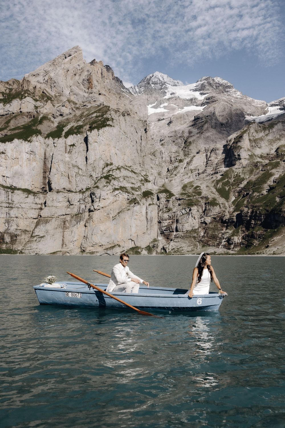 Romantic boat ride on a mountain lake with towering cliffs and glaciers creating a stunning backdrop.
