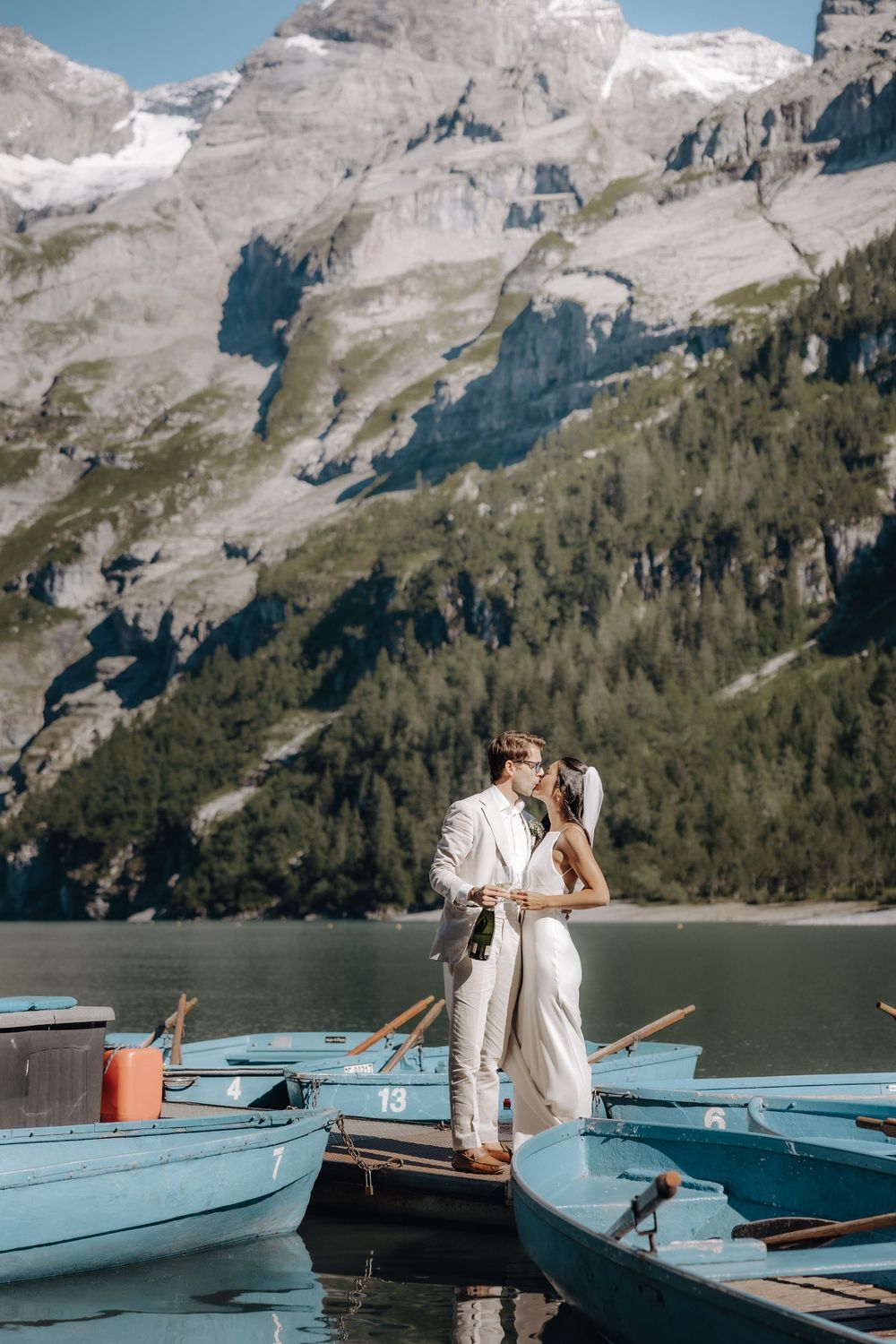 A couple shares an intimate moment on turquoise rental boats against a backdrop of majestic Swiss Alps.