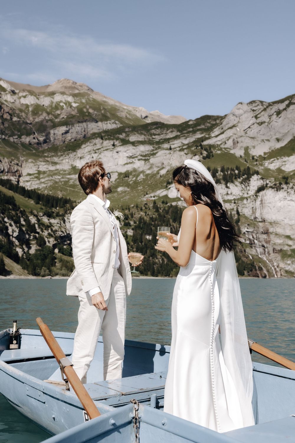 Wedding couple dancing together on a boat deck with dramatic mountain landscapes behind them.