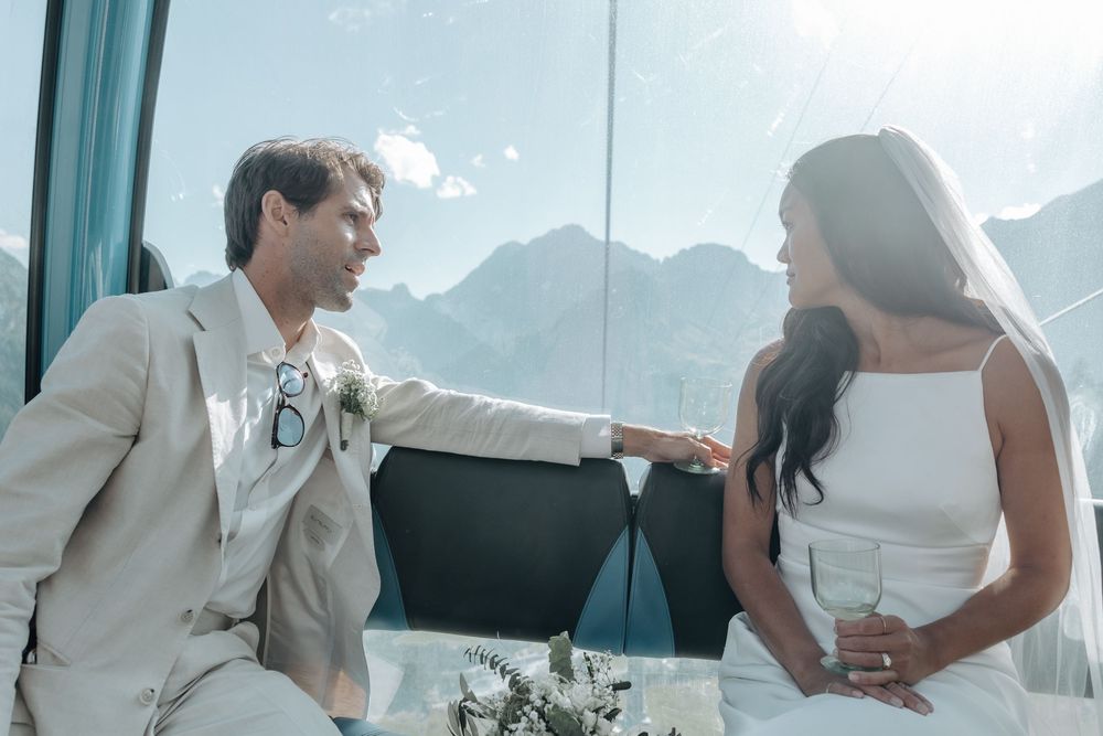 Wedding guests enjoy dancing and celebrating at an elegant reception with mountain views through large windows.