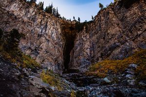 A panoramic view of towering granite cliffs and rocky walls in a scenic mountain landscape under blue skies.