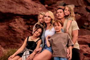 family snuggles together and stares off in the distance in Canonlands Moab, Utah
