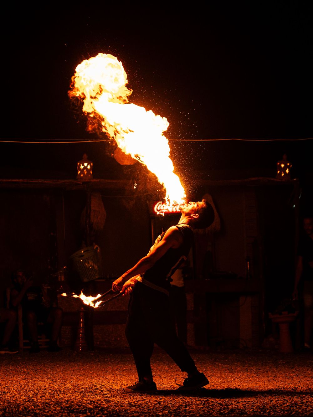 Cracheur de feu se produisant la nuit avec une explosion de flammes spectaculaire sur fond sombre. Florent Vause
