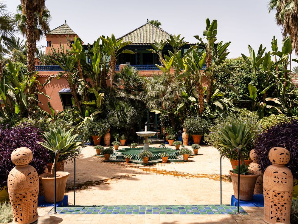 Jardin tropical avec des jardinières en terre cuite et des palmiers entourant une piscine turquoise. Florent Vause