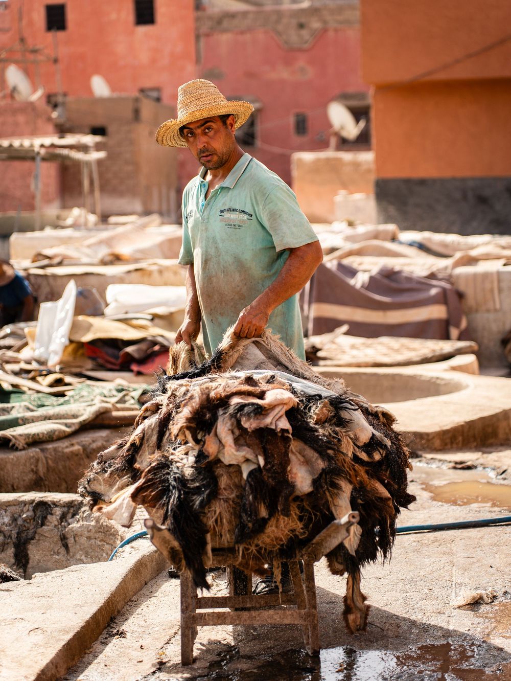 Ouvrier coiffé d'un chapeau de paille manipulant des peaux d'animaux dans une tannerie traditionnelle. Florent Vause