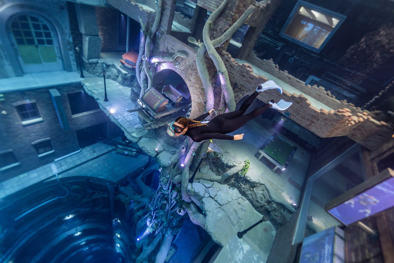 Futuristic underwater science lab interior with robotic arms and machinery illuminated by blue lighting in deep sea facility.