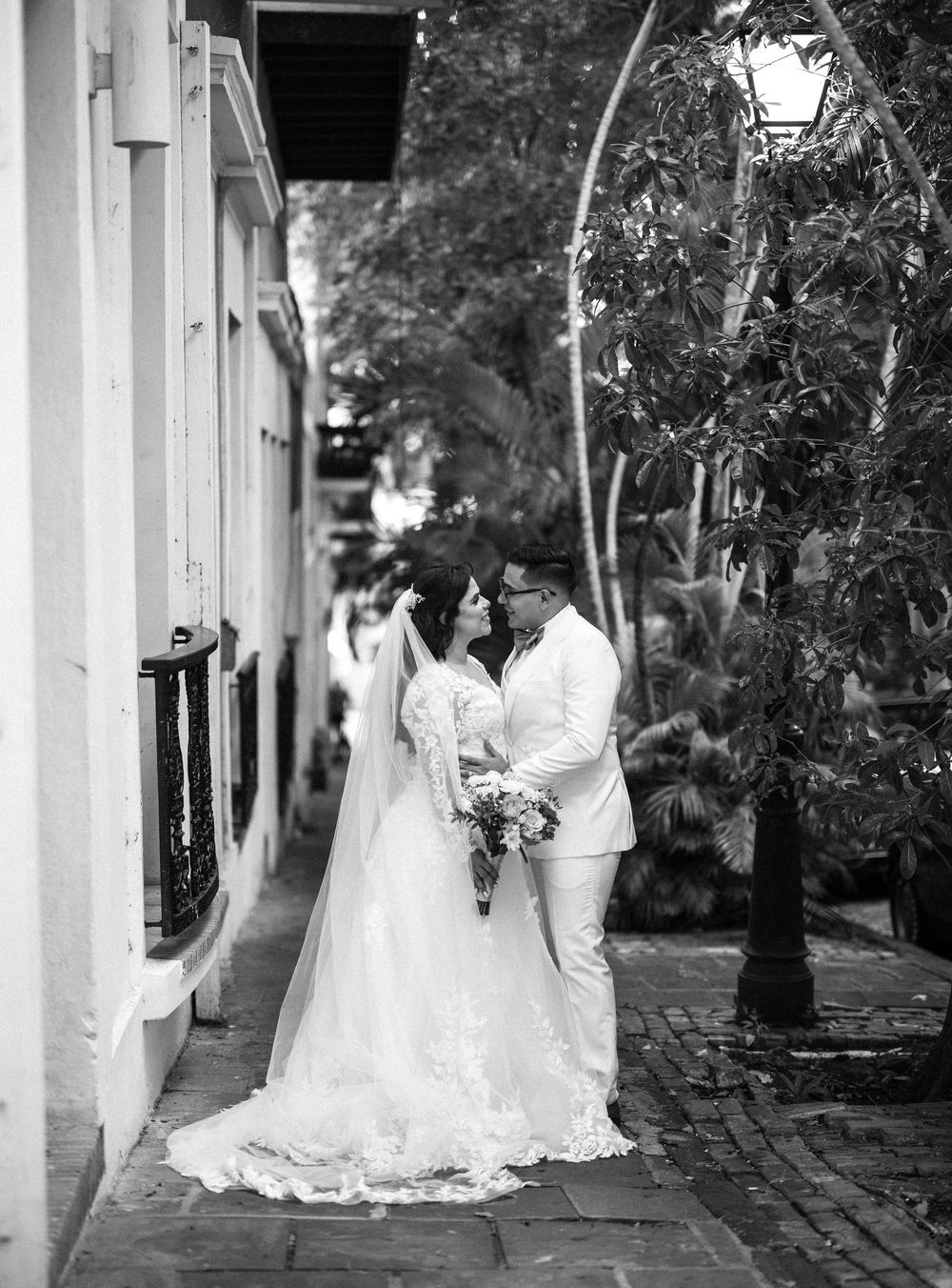 Romantic black and white wedding photography series showing couples in elegant bridal attire against colonnade walkway.