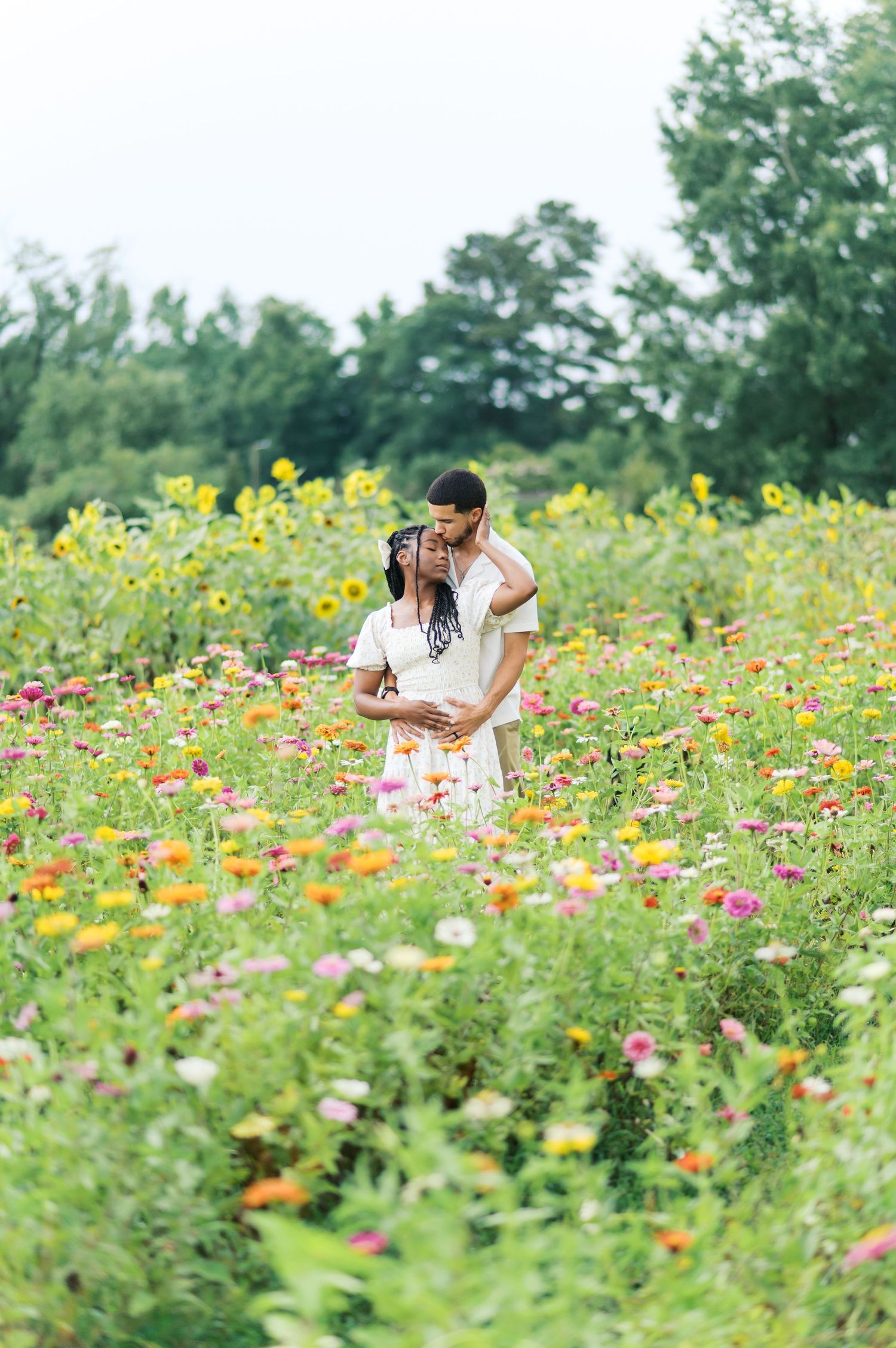 A couple embraces in a vibrant wildflower meadow filled with colorful summer blooms and greenery.