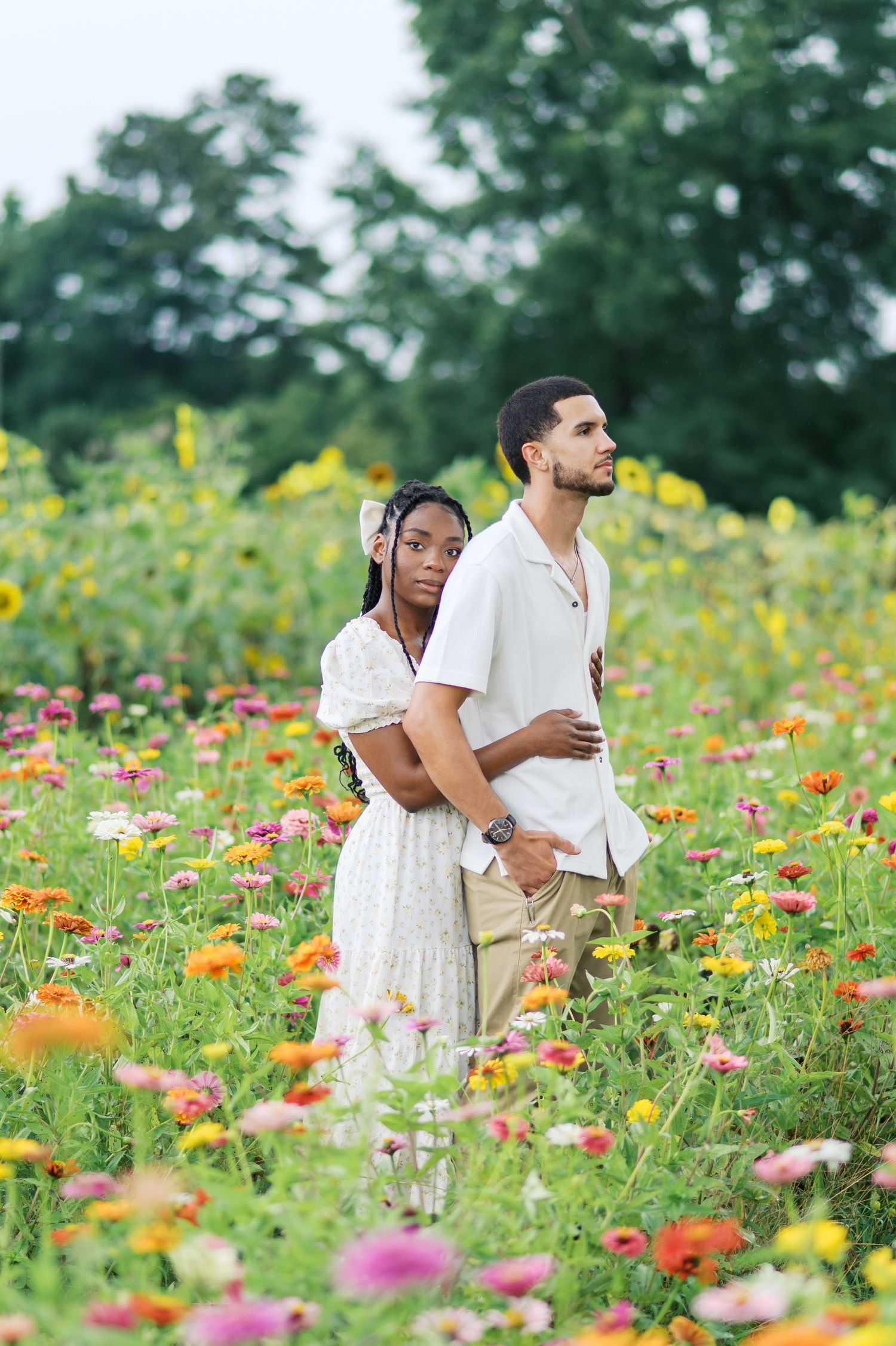 A couple stands together in a vibrant wildflower field filled with colorful blooms on a sunny summer day.