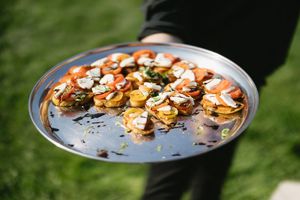 Shrimp grilled with garlic and seasonings sizzles on a round metal cooking pan outdoors.