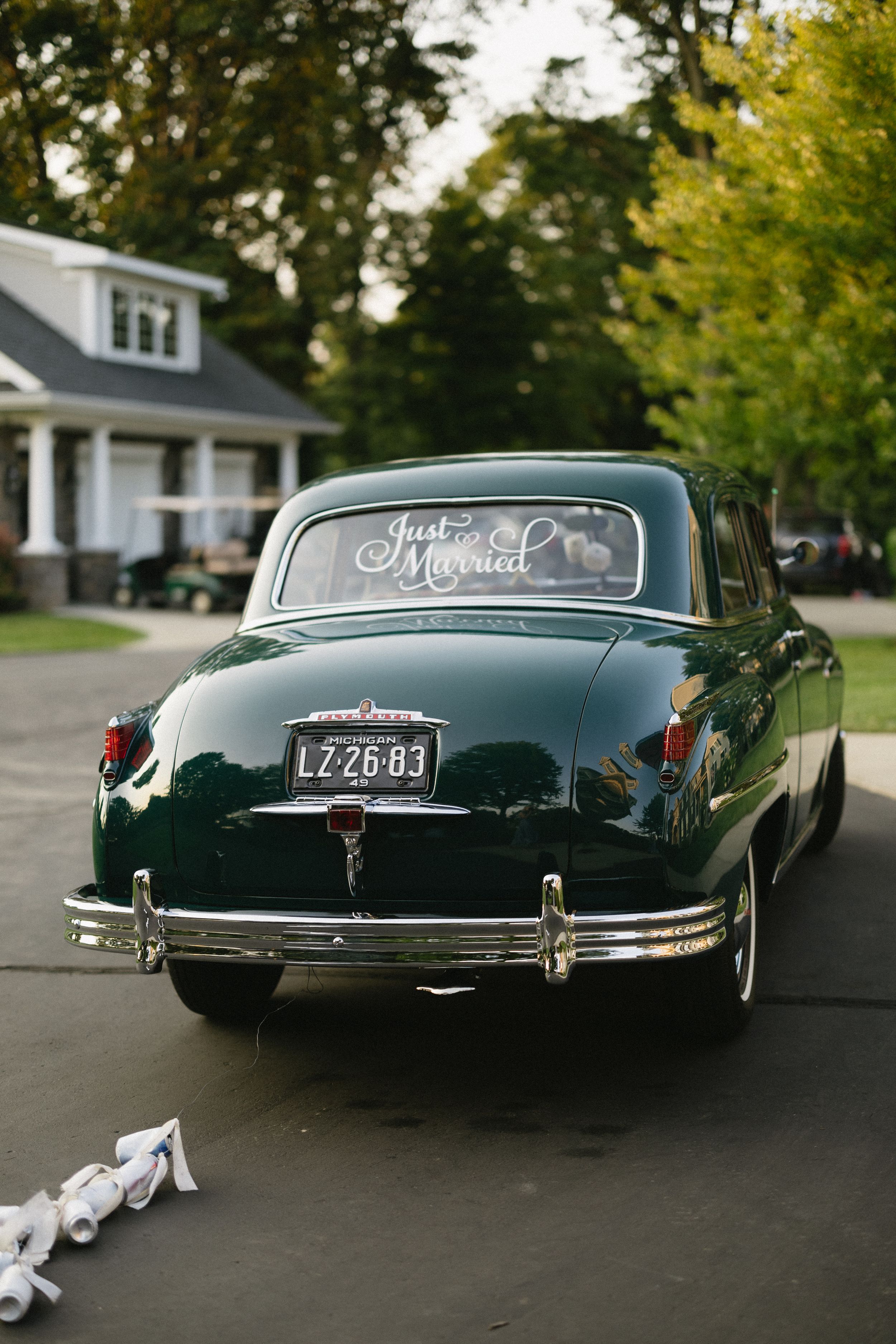 Elegant vintage black car decorated with white ribbons for a wedding, shown from three angles on a residential street.