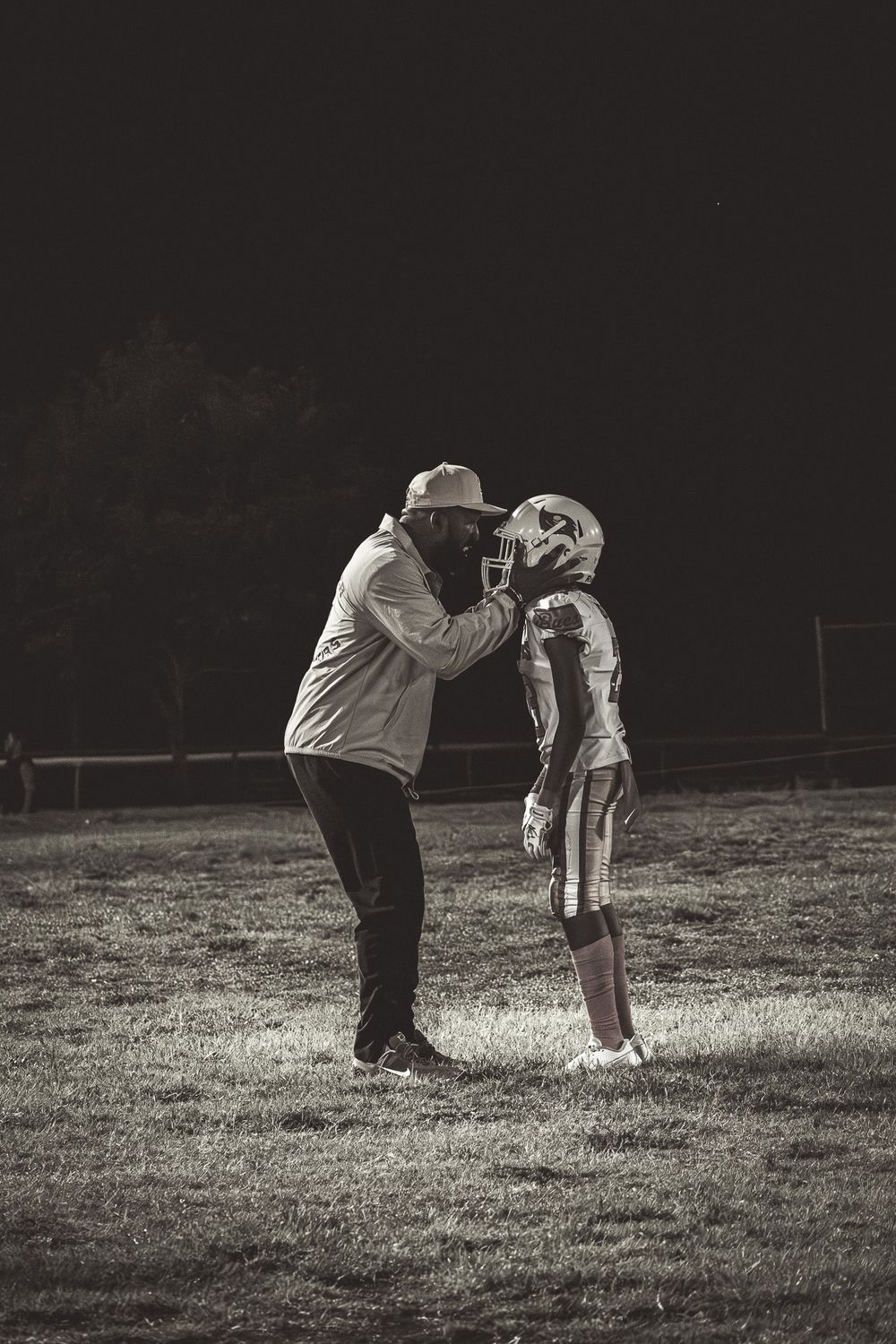 Coach gives instruction to player during nighttime football practice.