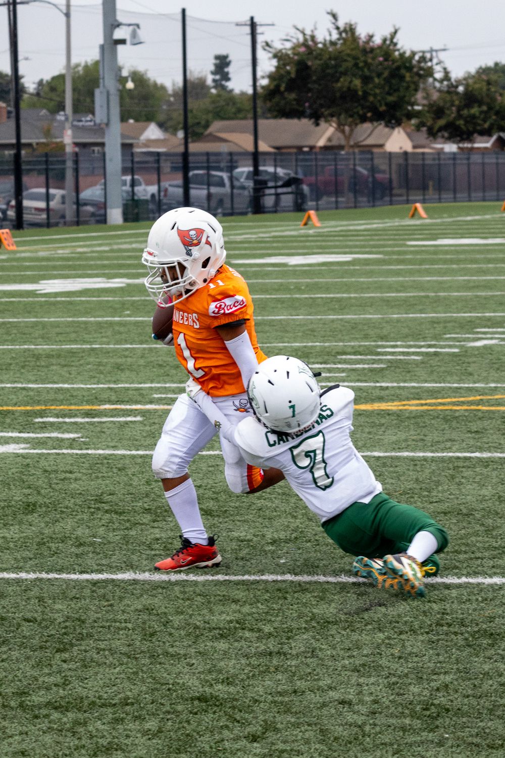 Defensive player making diving tackle attempt on ball carrier during football game.