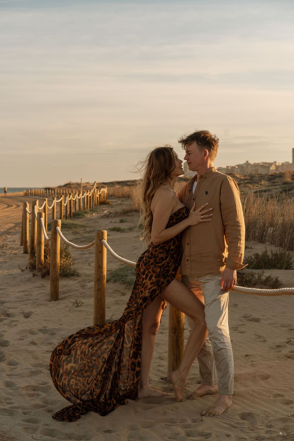 Romantyczna sesja narzeczeńska — zakochana para przytulająca się na plaży podczas zachodu słońca na Costa Blanca.