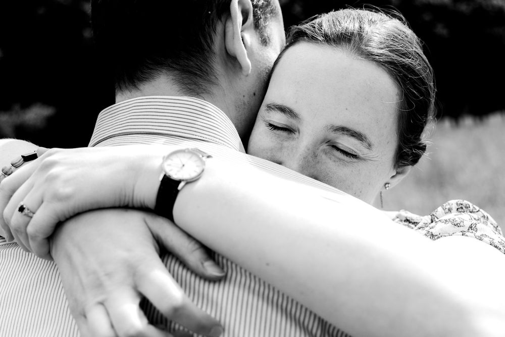 Black and white close-up of couple sharing tender embrace, bride smiling with eyes closed.