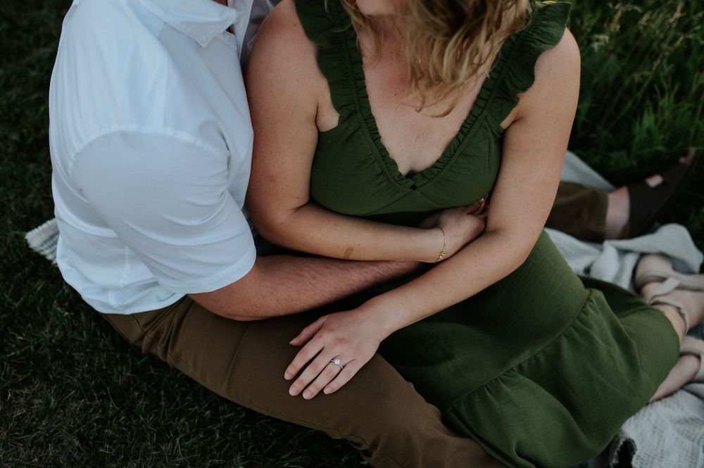 A romantic couple in olive green and white casual attire shares intimate moments in a garden setting.