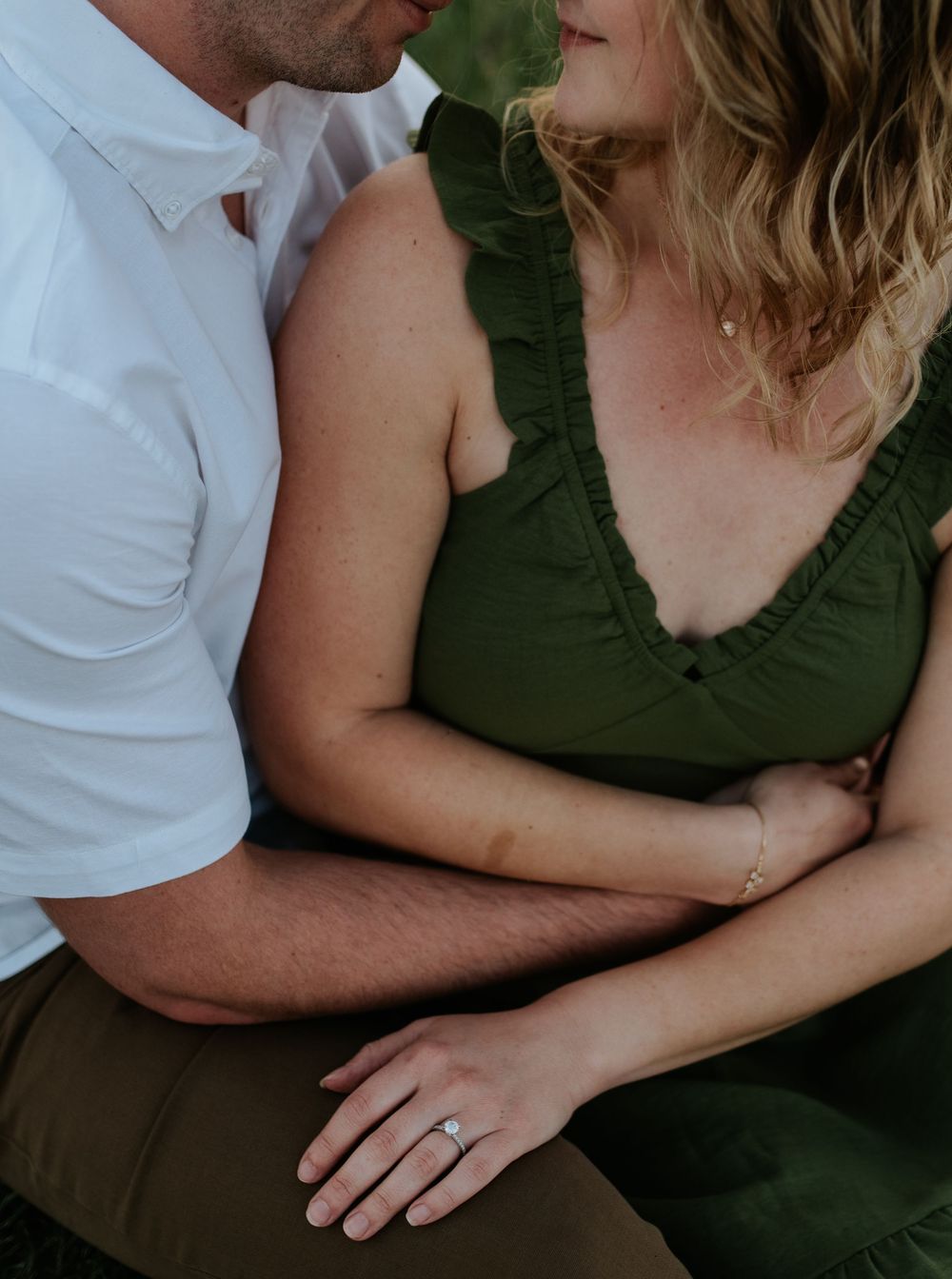 Close up portrait of a romantic couple embracing, with her wearing a green dress and him in a white shirt.