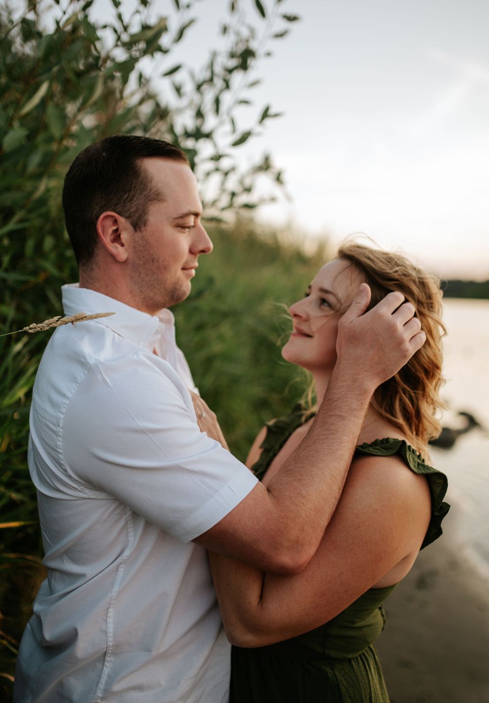 A romantic couple shares intimate moments at sunset by the water, caught in a series of candid embraces.