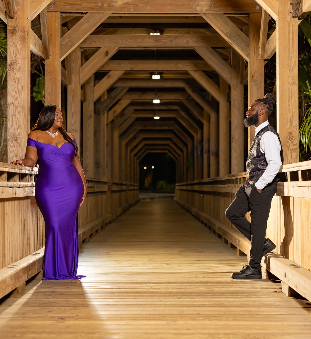 Rustic wooden covered walkway with elegant couple posing in formal attire.