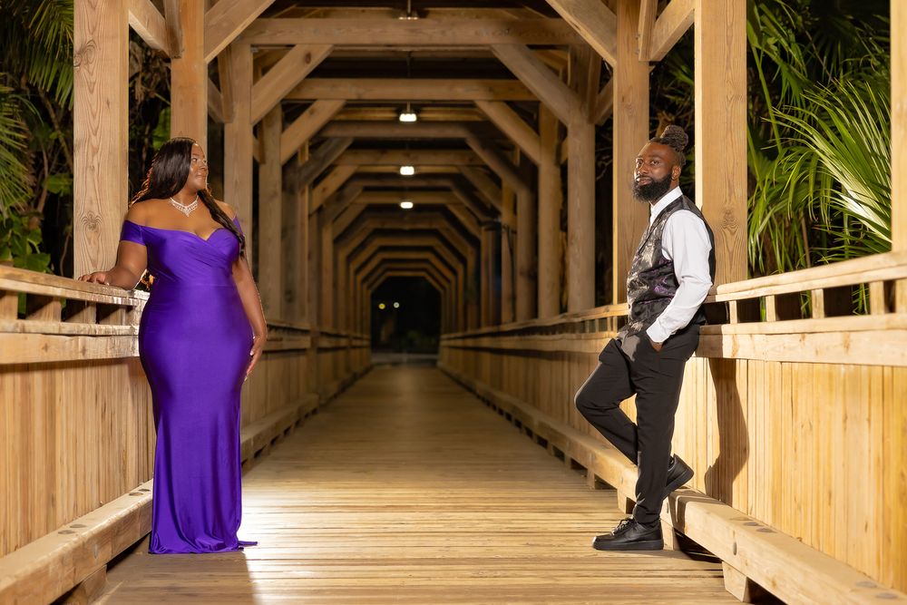 Elegant photo session in wooden covered walkway with purple gown and formal wear.