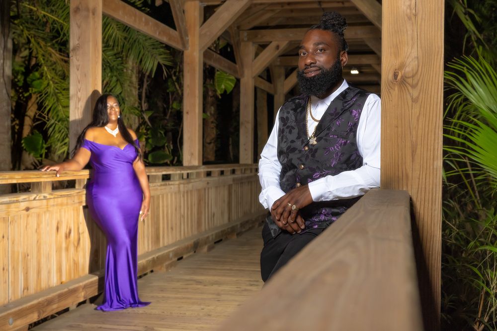 Evening photoshoot in wooden covered walkway with formal attire and dramatic lighting.