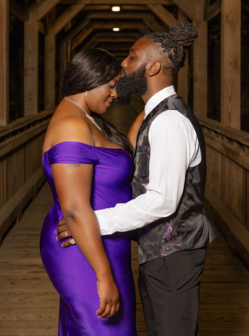 A romantic embrace captured in a wooden corridor with ambient lighting.
