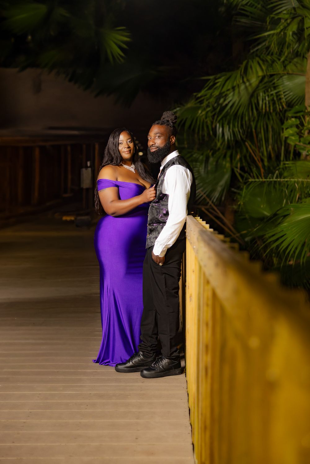 A romantic moment captured on a covered wooden path with a couple in elegant evening wear.