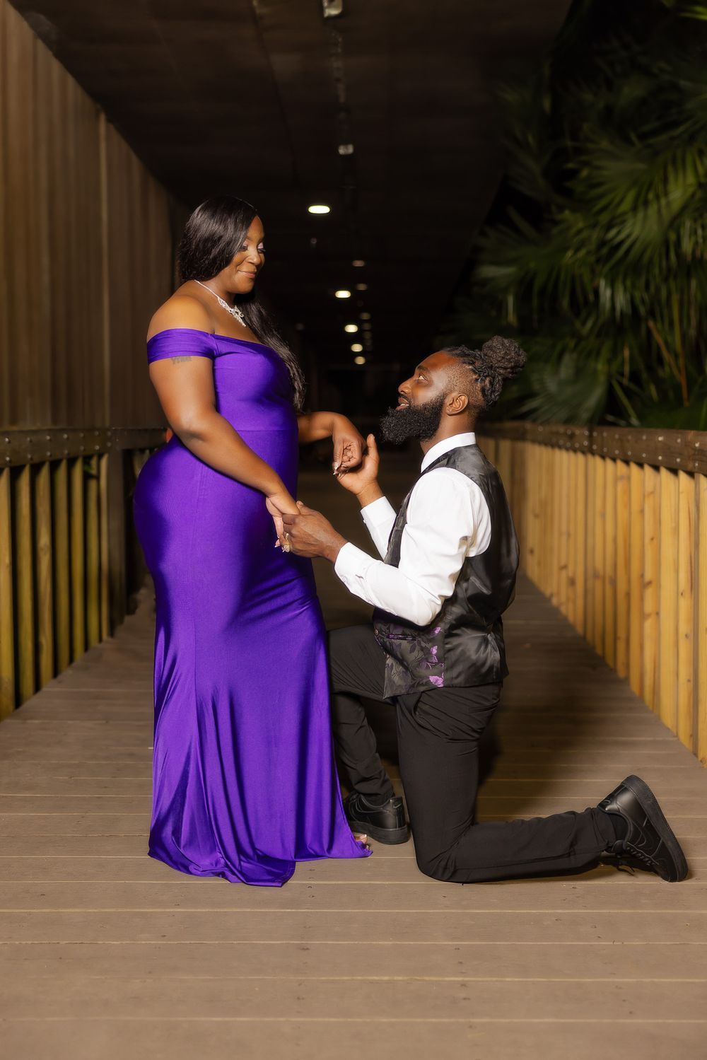 A proposal moment captured on a wooden boardwalk with one person kneeling.