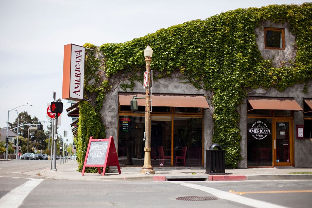 A restaurant storefront with ivy-covered walls and signage on a street corner.