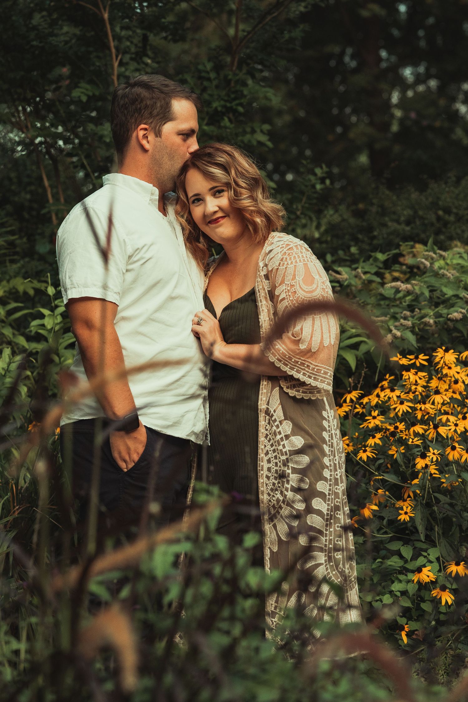 Couple Portraits of man in a white button down shirt facing woman wearing black dress with tan sweater resting her head on his chest.