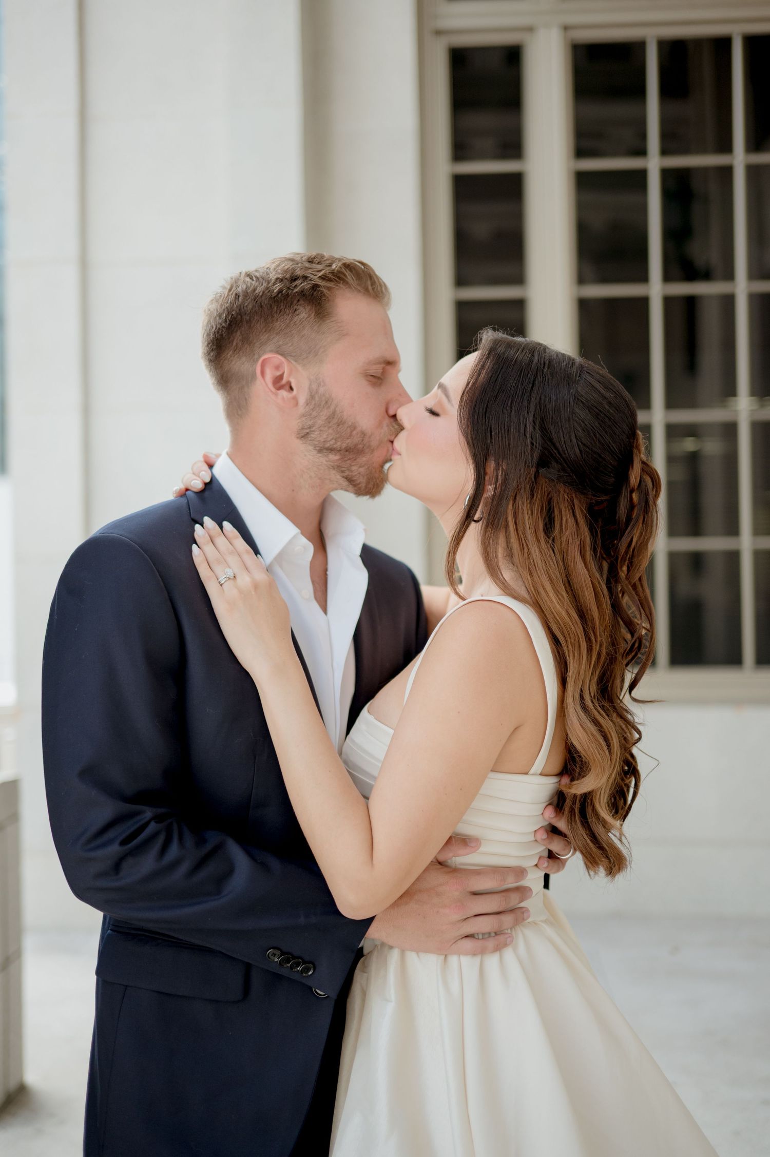 Romantic wedding couple sharing tender kisses in a series of intimate moments against a white columned backdrop.