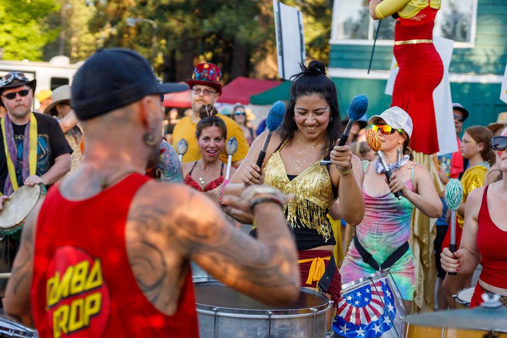 Festive outdoor drum circle with colorful performers playing steel drums at High Sierra Music Festival