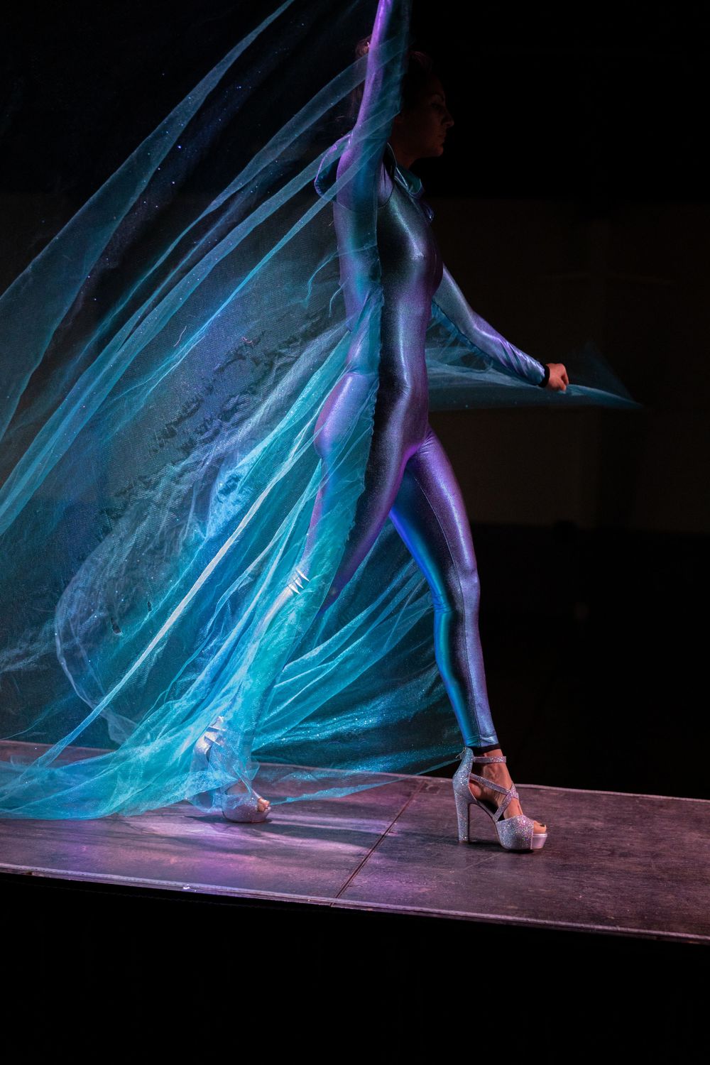 Artistic dance performance featuring flowing blue fabric and dramatic lighting on stage.