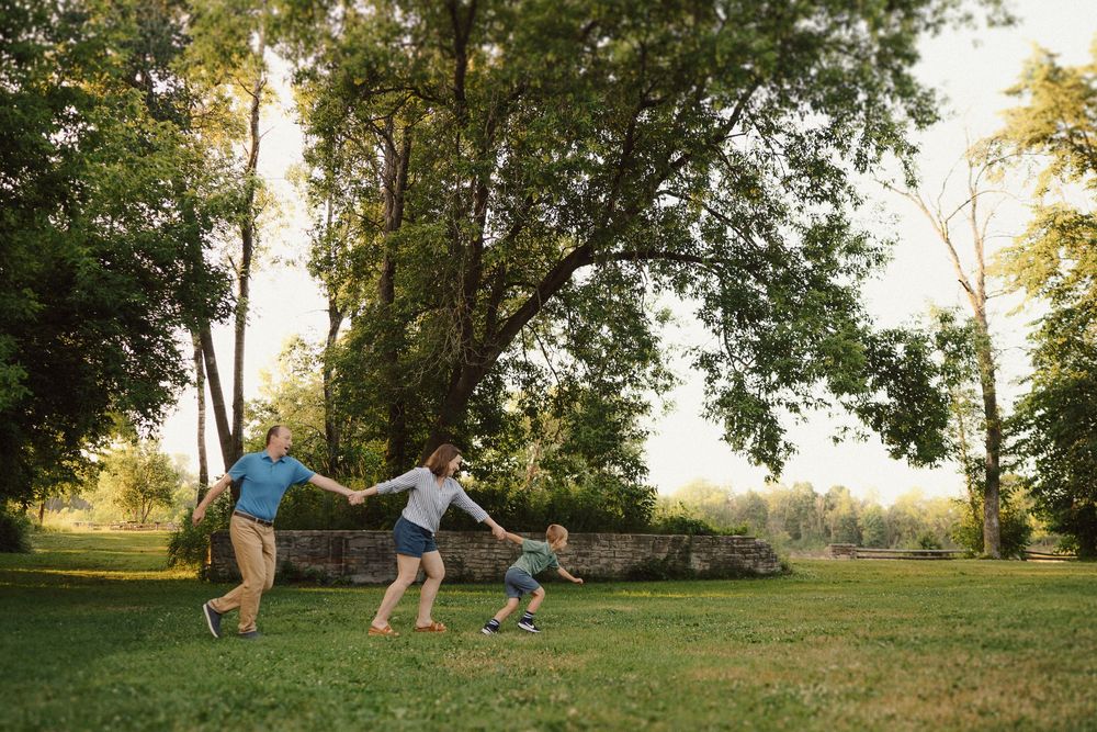Family shares playful moments together on a grassy hill during sunset at an outdoor photo session.