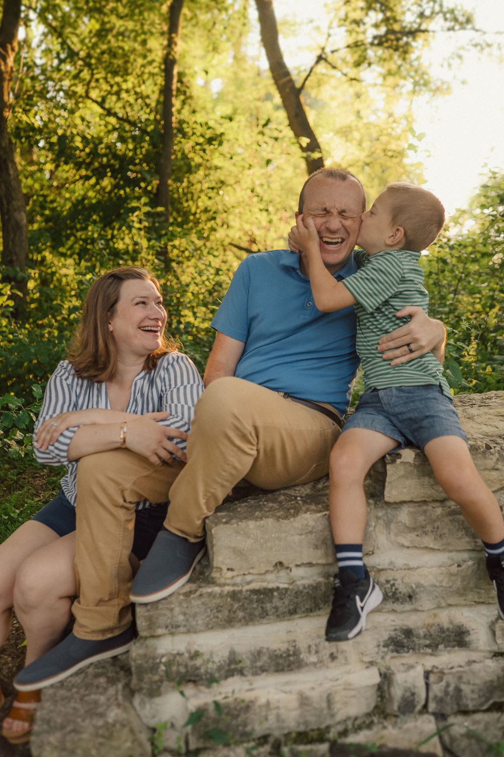 People sit together on a stone wall sharing joyful moments during a golden hour photo session.