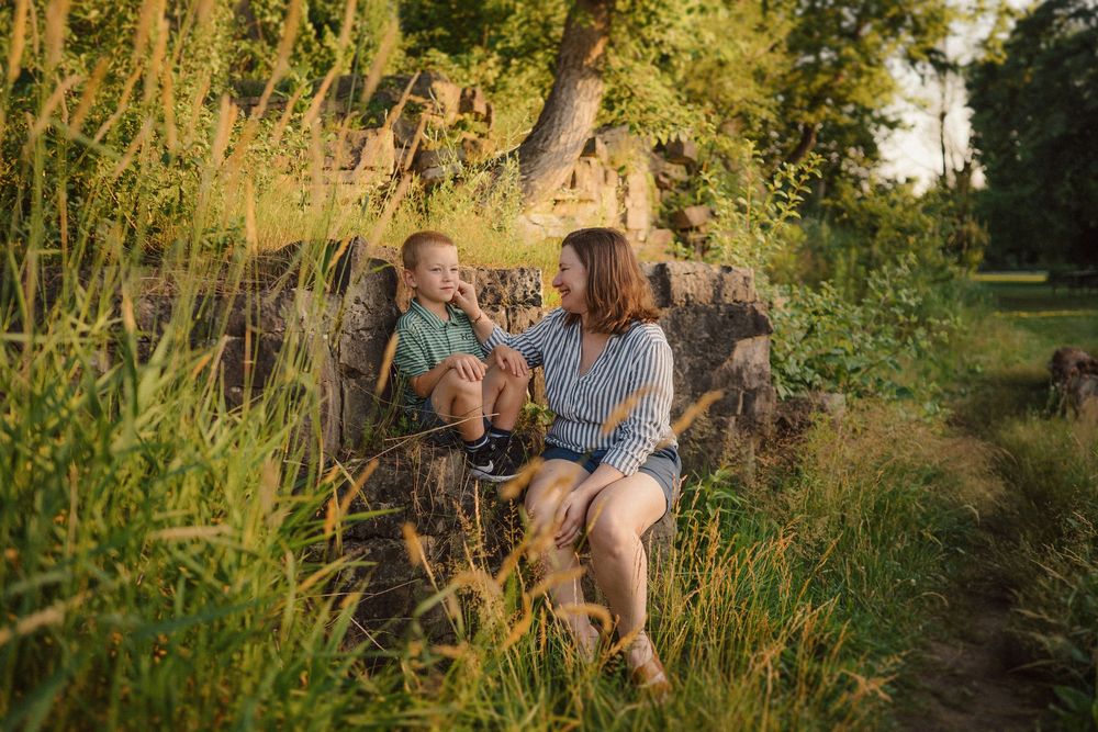 Candid family moments captured in tall grass during sunset.