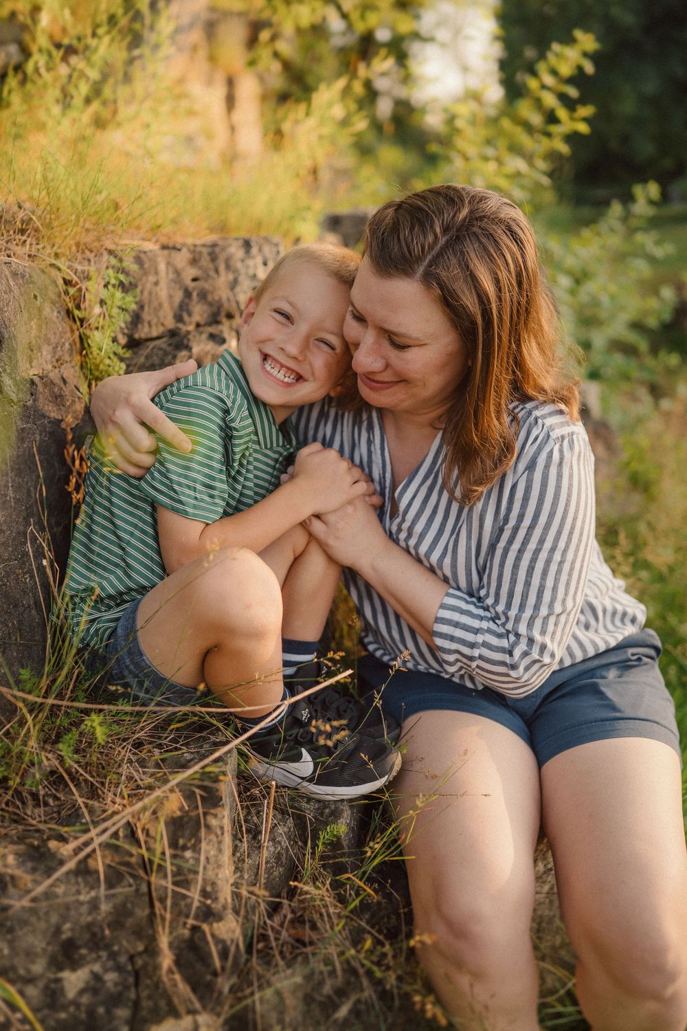 A tender moment shared between parent and child sitting together outdoors in warm sunlight.