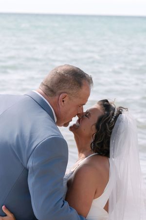 A romantic sequence of beach wedding photos showing a couple sharing an intimate kiss by the ocean.
