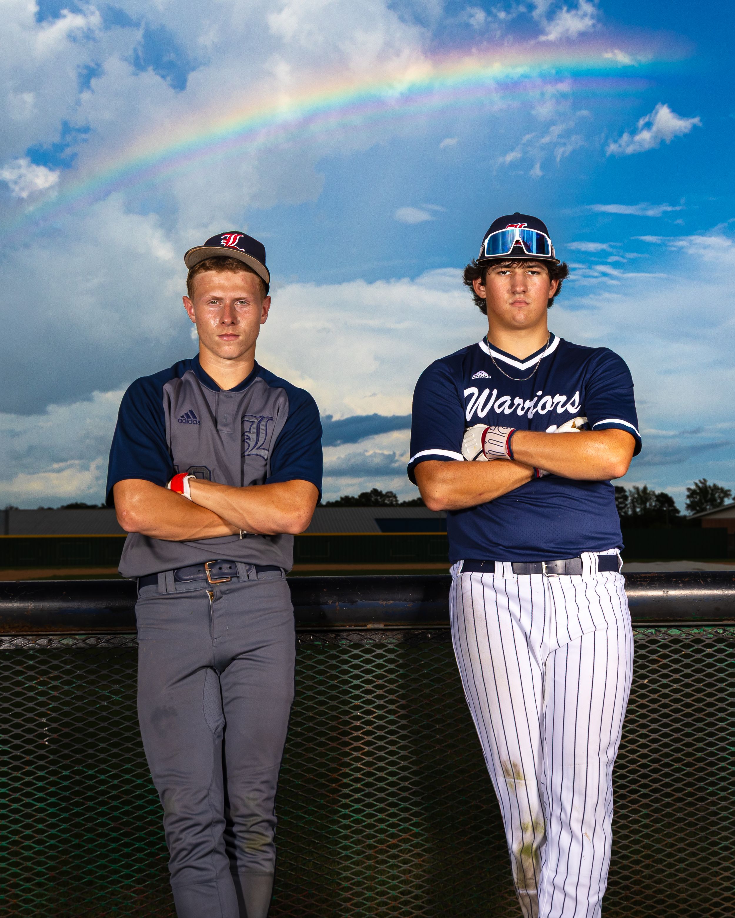 Baseball players in gray and pinstripe uniforms pose for dramatic portraits against a cloudy sky with rainbow backdrop.