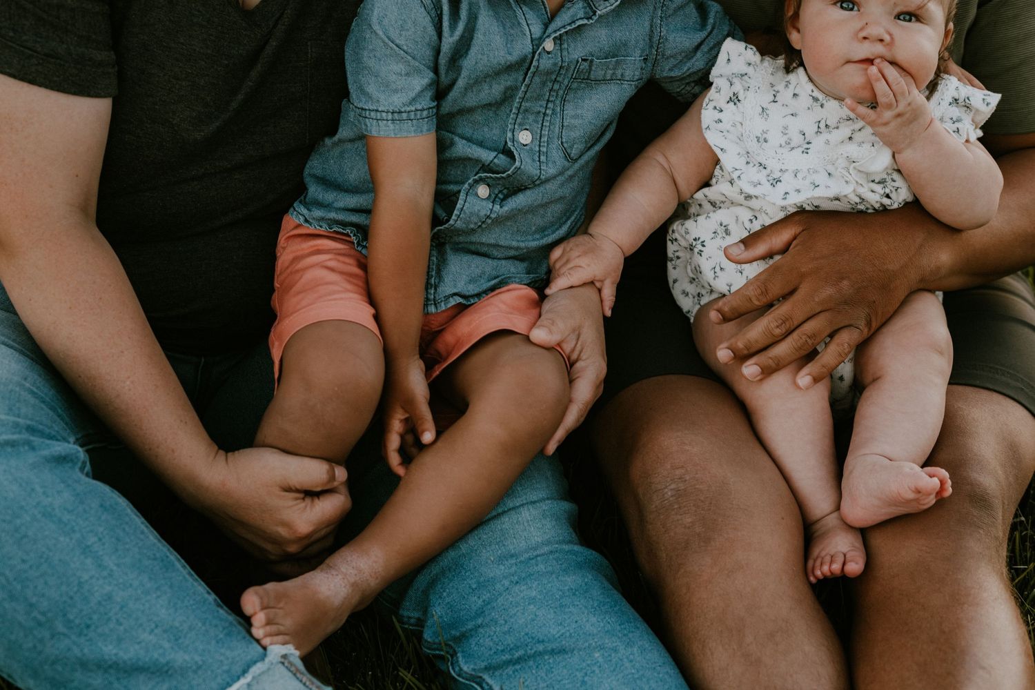 Close-up view of family members sitting together on couch showing legs and casual attire.