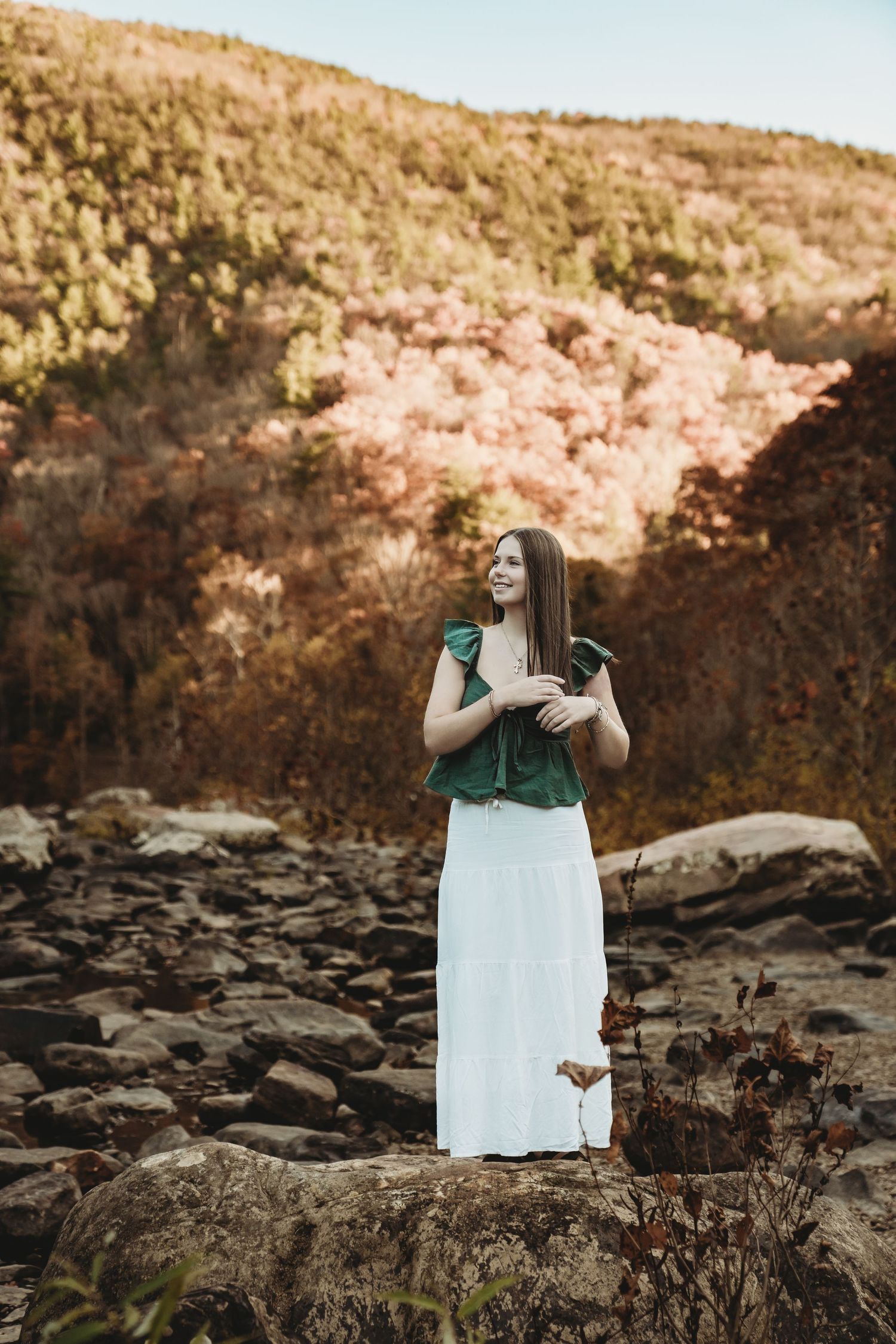 A white dress flows in the breeze against a rocky coastal backdrop during golden hour.