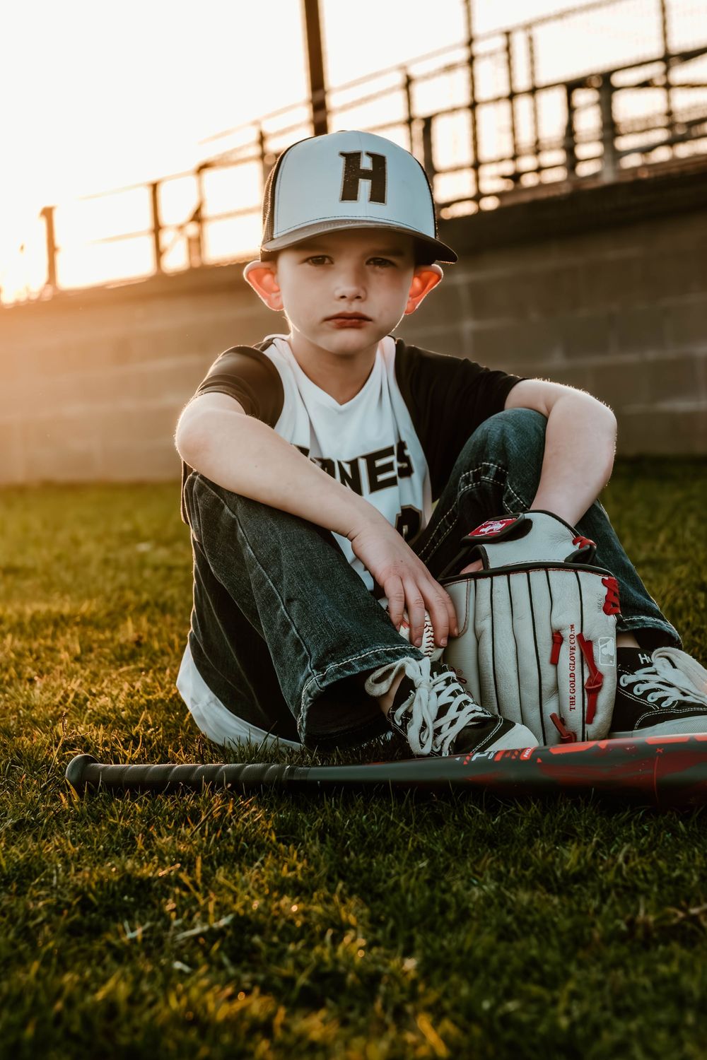 Baseball player reclines on grass field at sunset wearing team uniform.