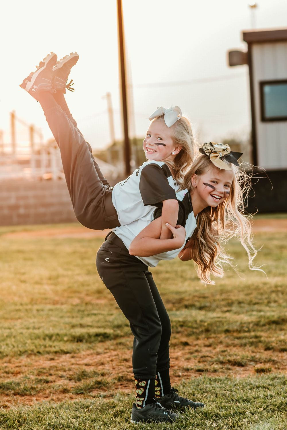 Playful softball players having fun and laughing on field at sunset.