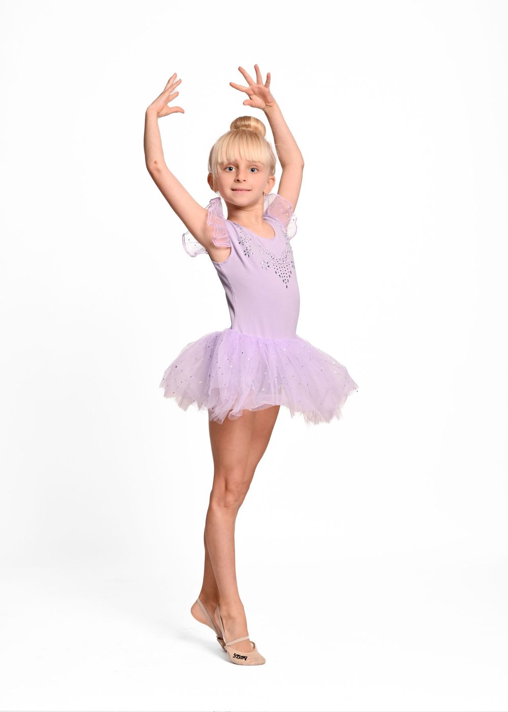 A young ballet dancer in a purple tutu performs graceful poses in a series of four dance positions.