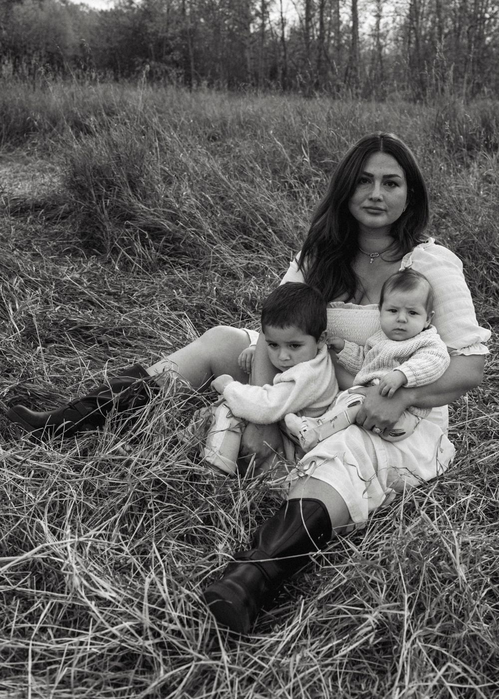 A black and white photo series shows people relaxing together in tall grass, creating an intimate outdoor portrait setting.