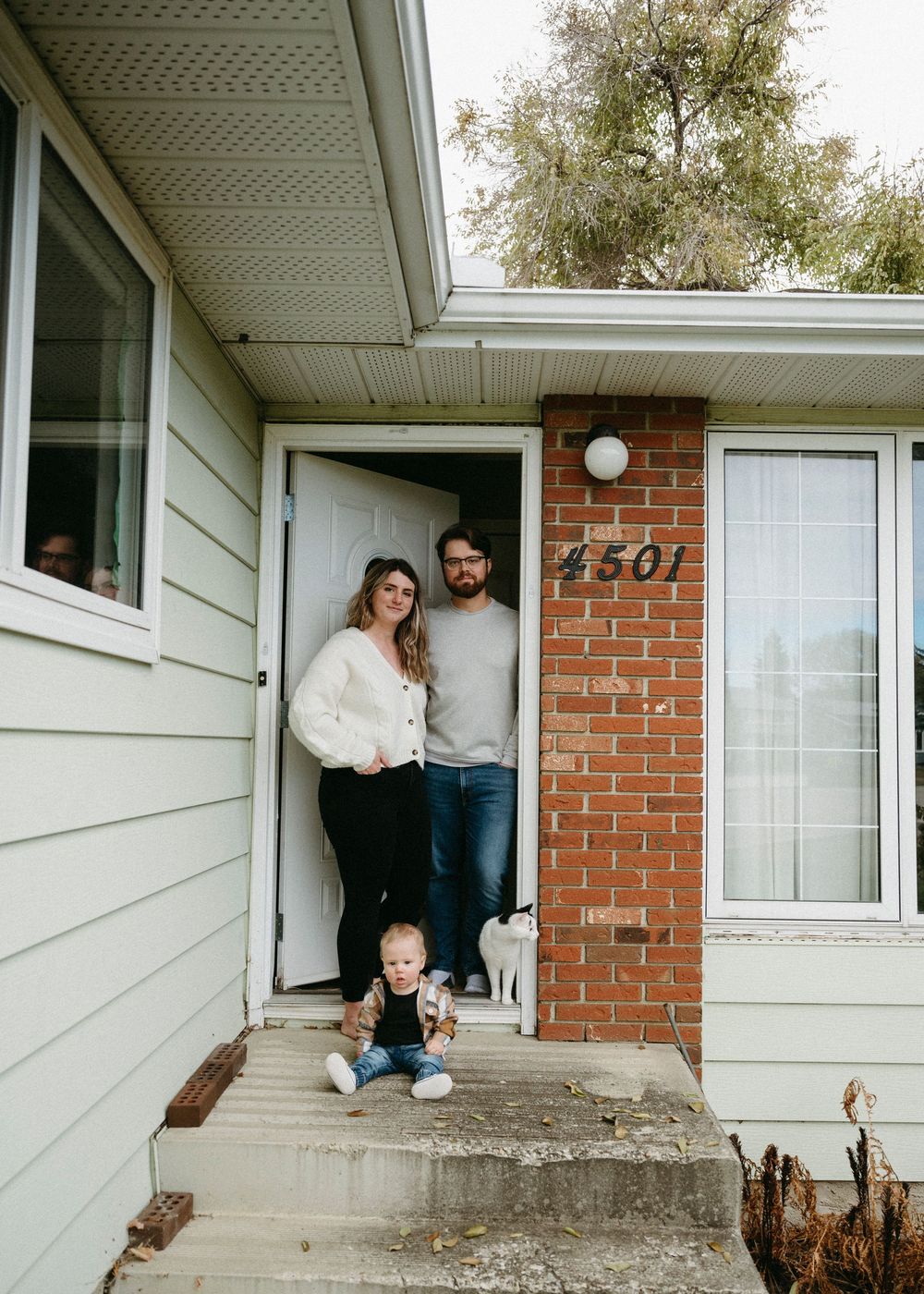 Series of photos showing people sitting in windows and doorways of a brick house with white trim.