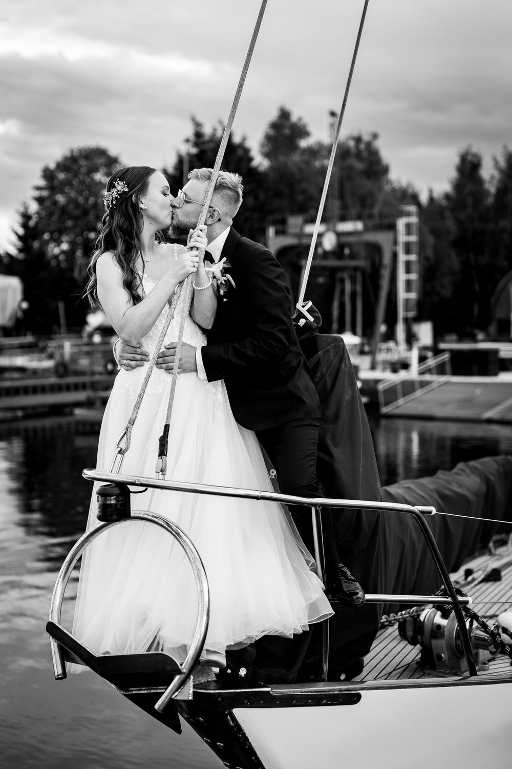 A romantic wedding photo shoot on a boat dock with water in the background.
